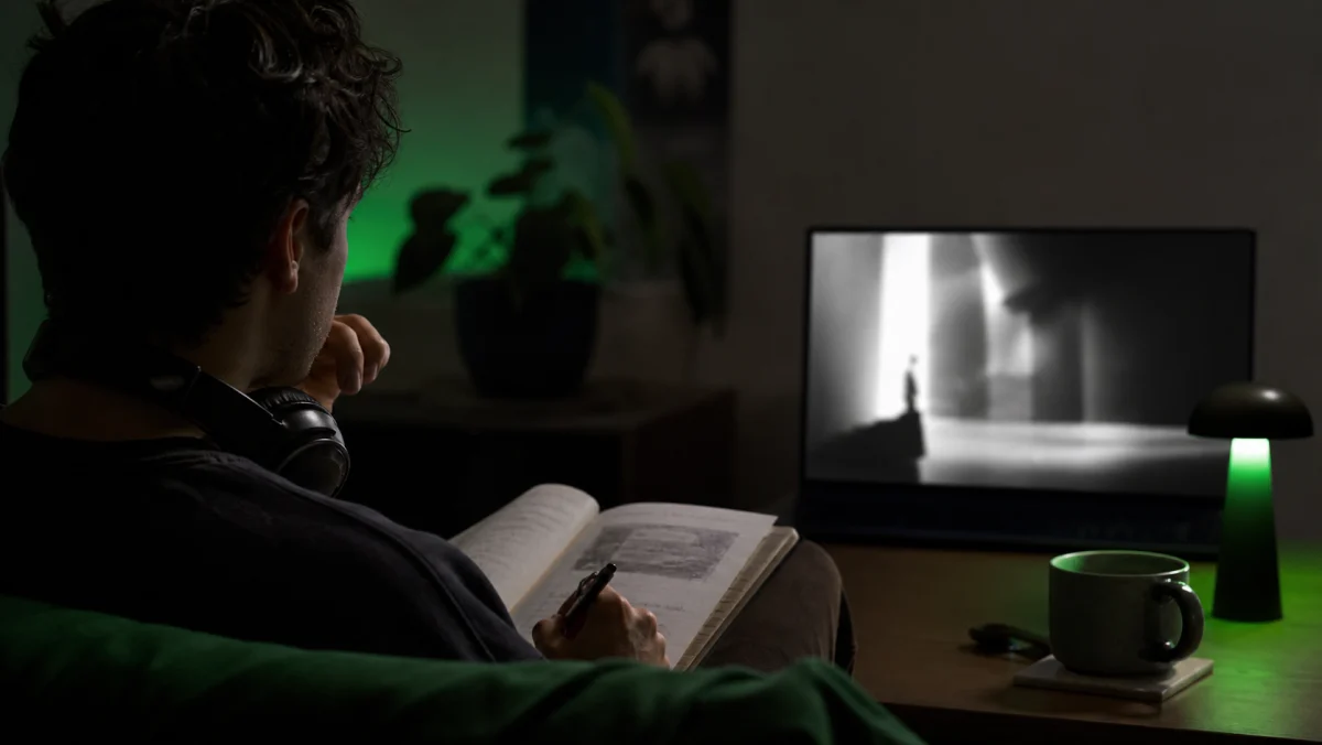Spectateur concentré prenant des notes devant un film abstrait en noir et blanc.